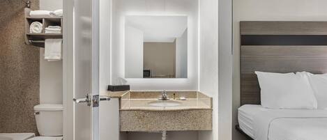 Ein Badezimmer mit Toilette, Waschbecken und einem Bett mit weißer Bettwäsche.