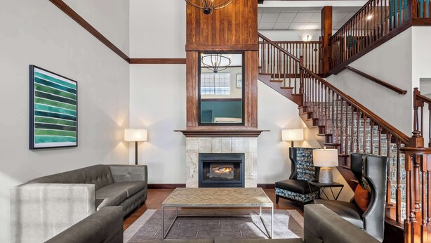 A spacious living room with a fireplace, a staircase, and modern furniture.