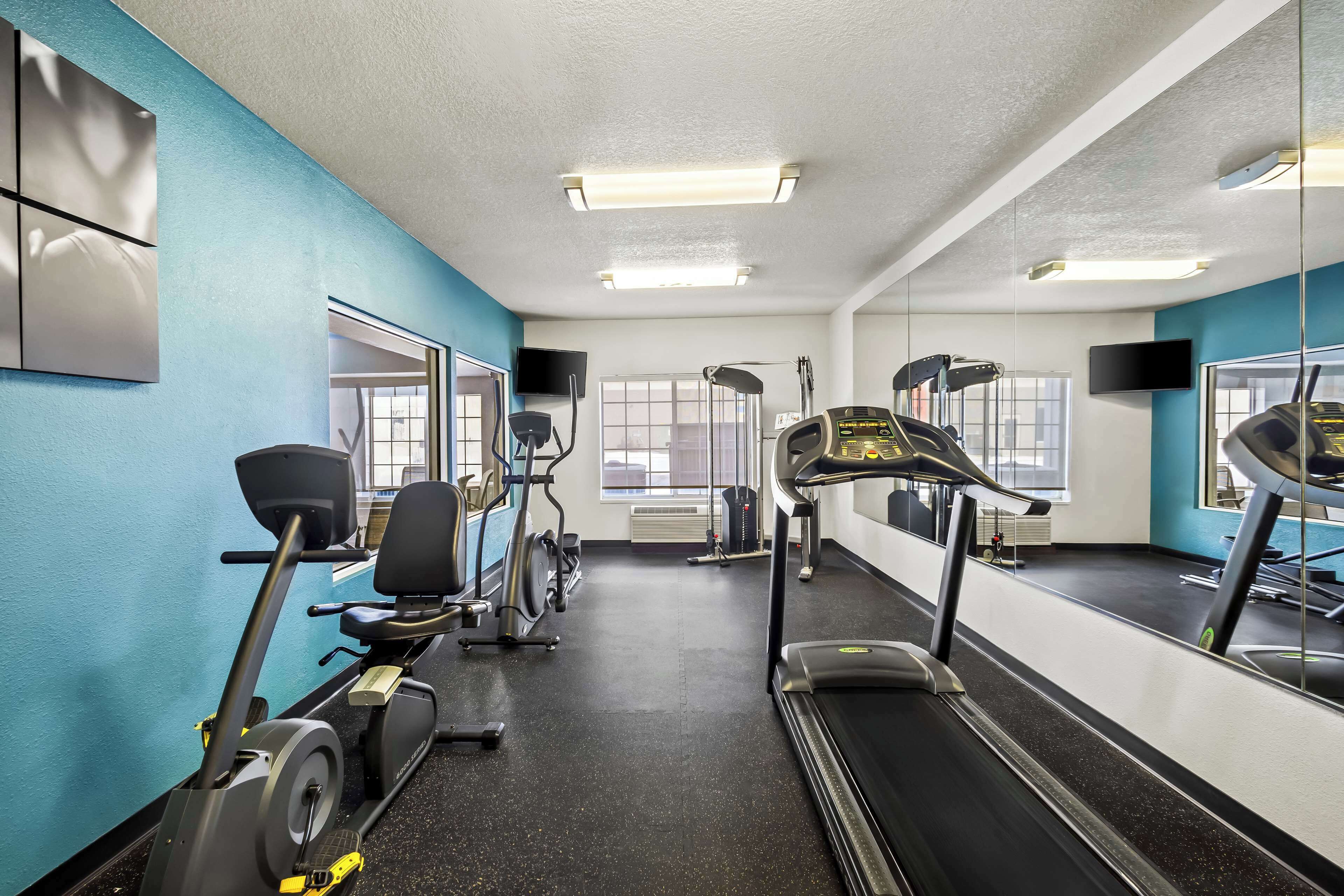A gym with cardio equipment, mirrors, and large windows.