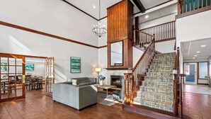 A spacious living area with a fireplace, a staircase with wooden railings, and a dining area with a view of the kitchen.
