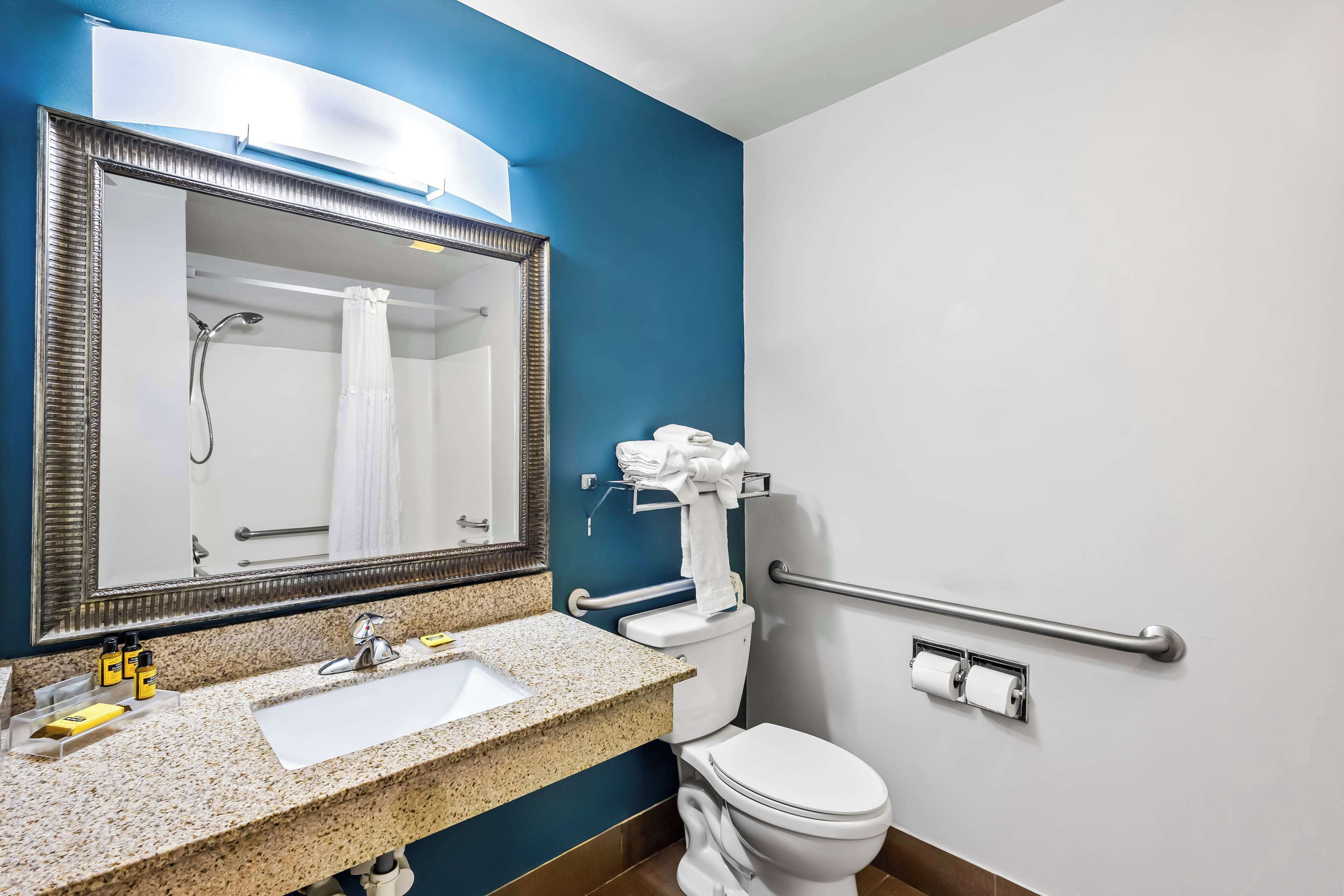 Un baño con lavabo, espejo, inodoro y barandilla.