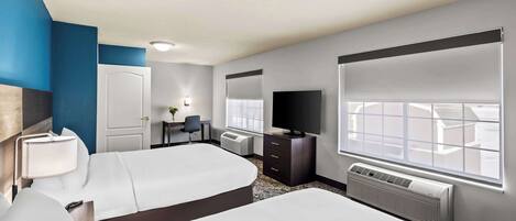 A hotel room with two beds, a desk, a chair, a TV, and a large window.
