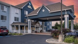 A Best Western hotel with a covered entrance, a parking lot, and a sunset sky.