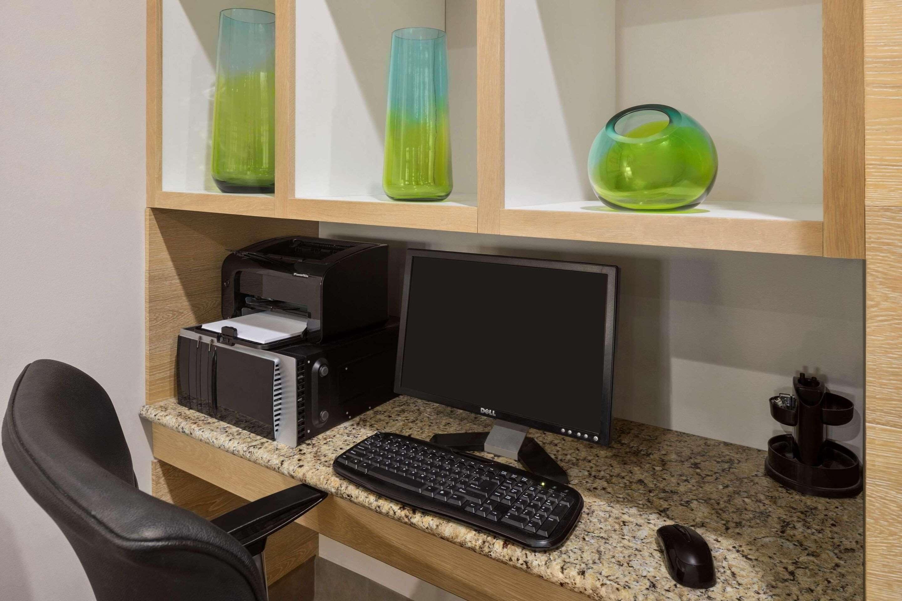 Un espace de travail aménagé à la maison, comprenant un ordinateur de bureau, un clavier et une souris, le tout installé sur un comptoir en granit.
