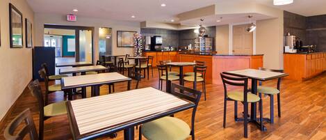 Un restaurante con mesas y sillas de madera, una zona de cocina y un letrero de salida.