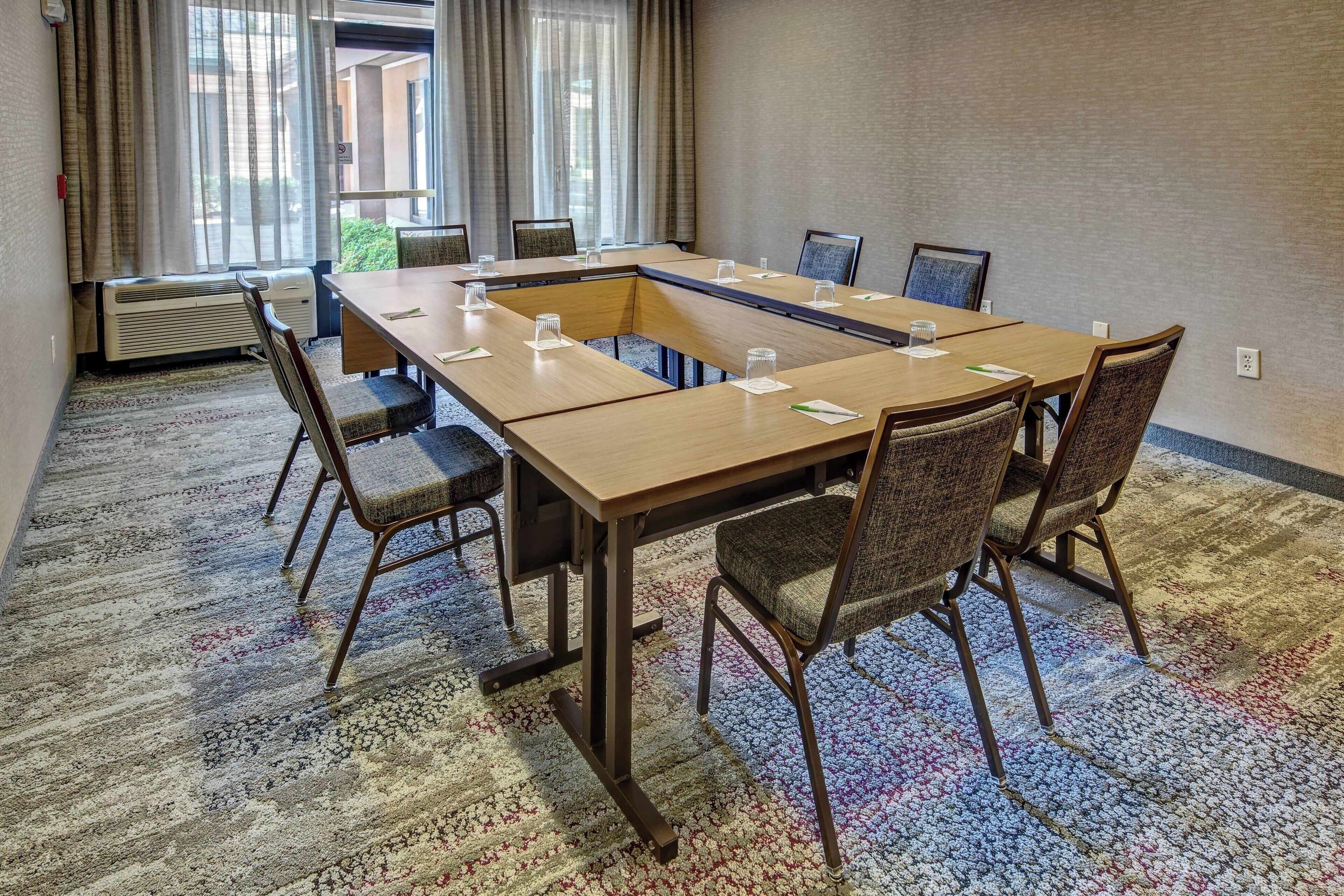 A conference room with a long table, chairs, and a carpeted floor.