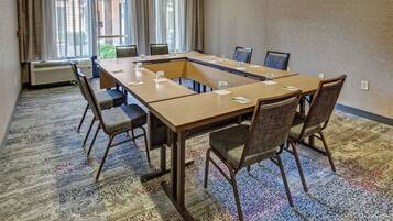 A conference room with a long table, chairs, and a carpeted floor.