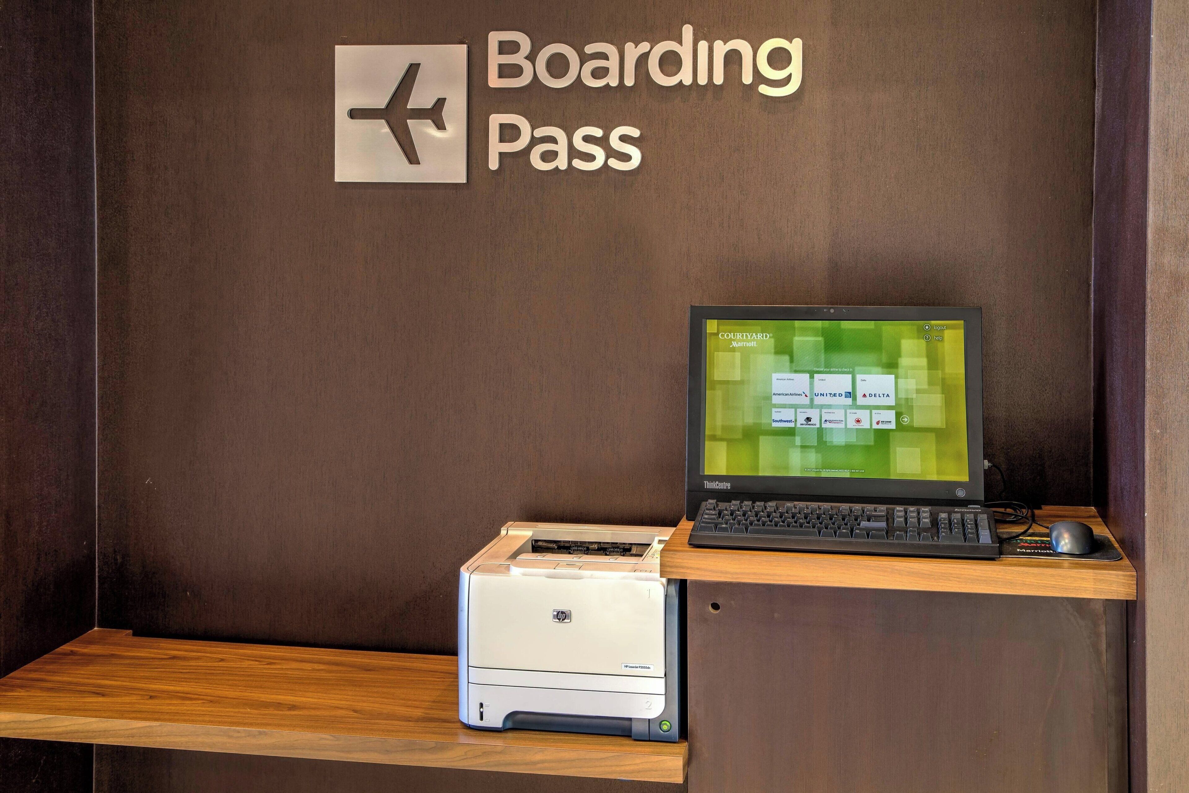 A desk with a laptop, a printer, and a sign reading "Boarding Pass".