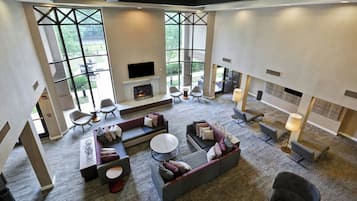 A spacious living area with a fireplace, comfortable seating, and large windows offering a view of the outdoors.