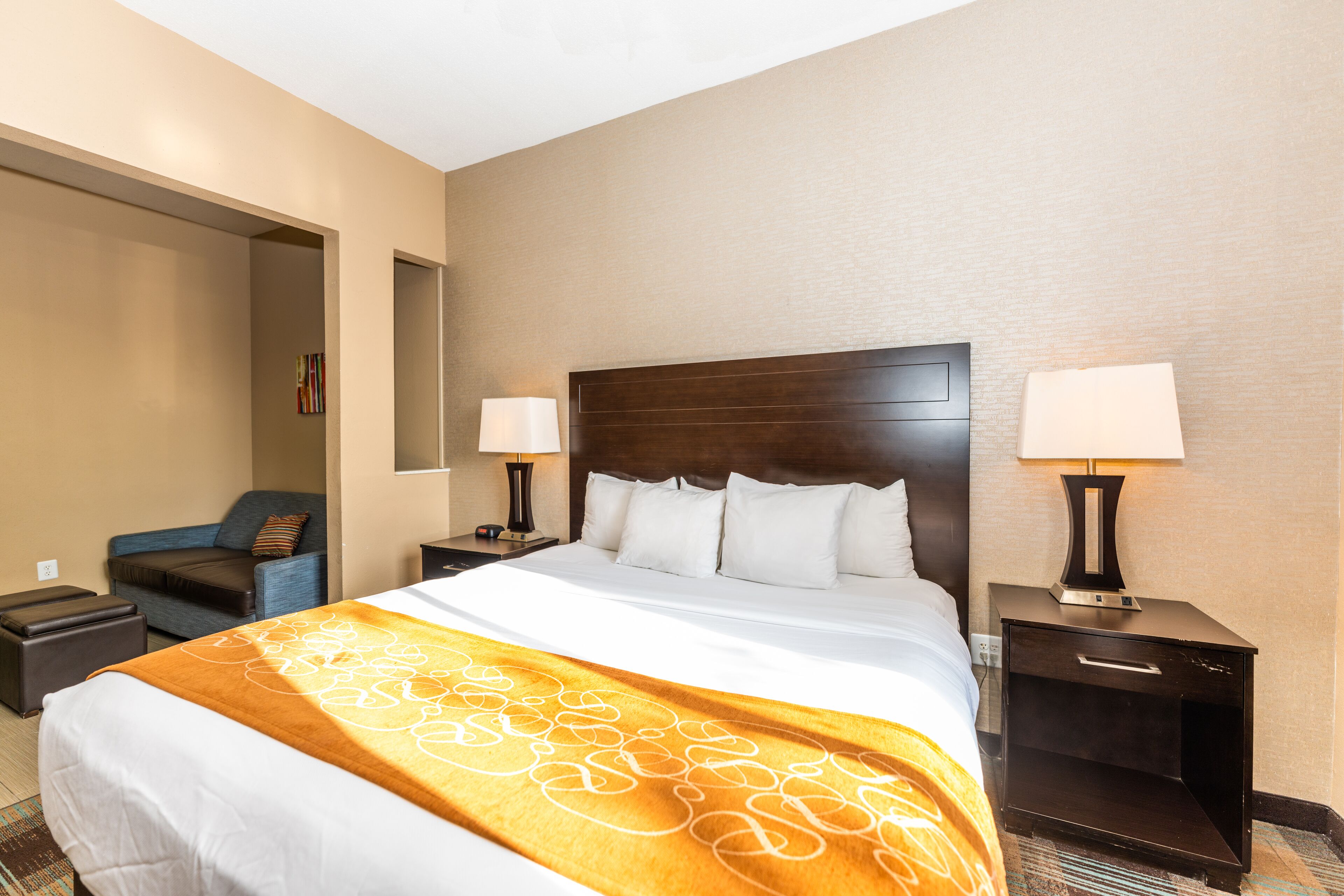A hotel room with a large bed, two bedside tables, a nightstand, a chair, and a wall-mounted TV.