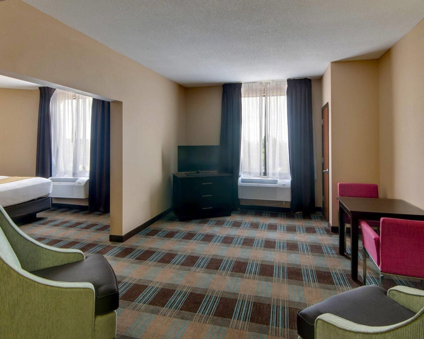 Habitación de hotel con cama, televisión, escritorio y dos sillas.