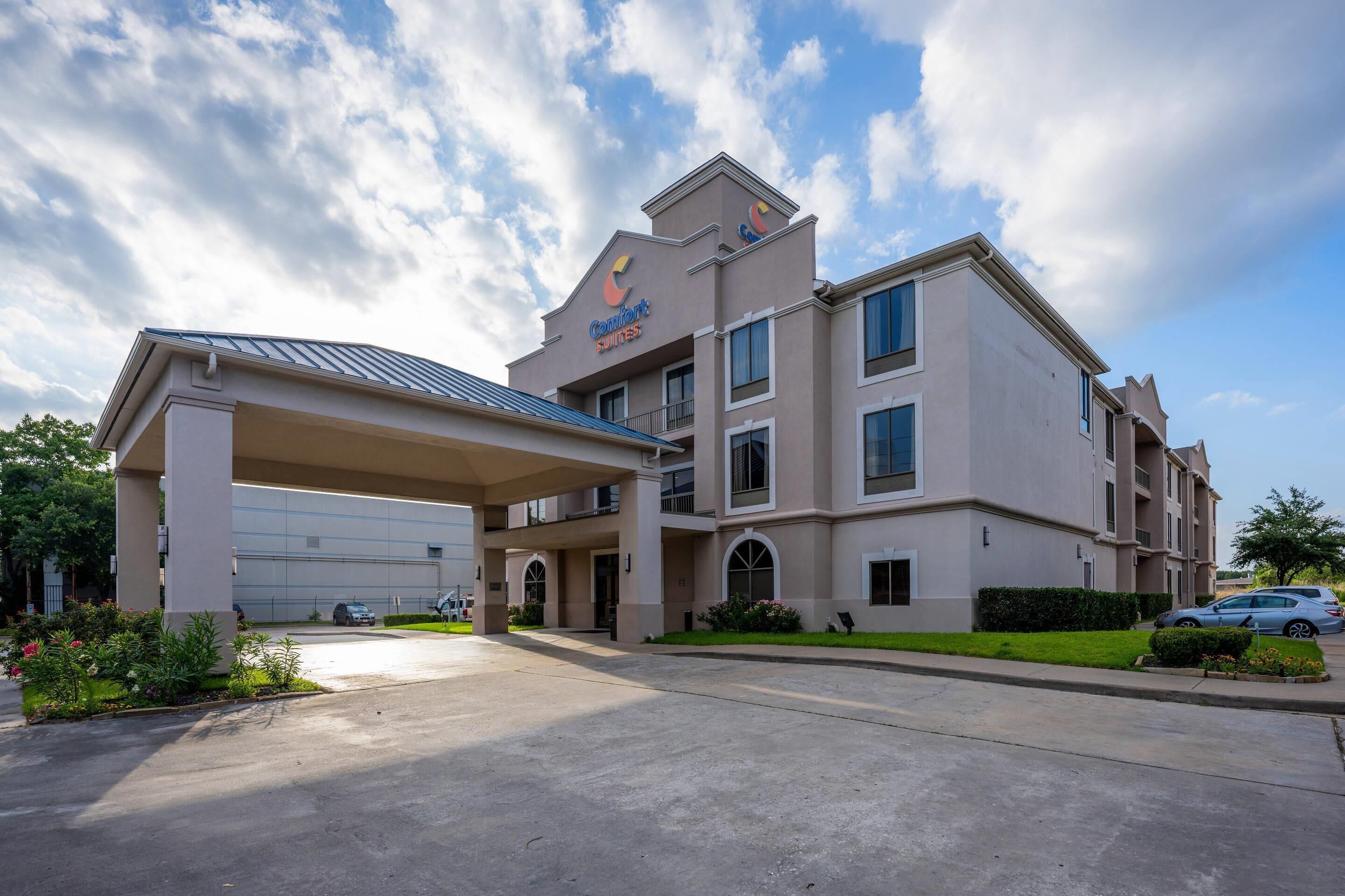 A hotel with a covered entrance, multiple floors, and a parking area.