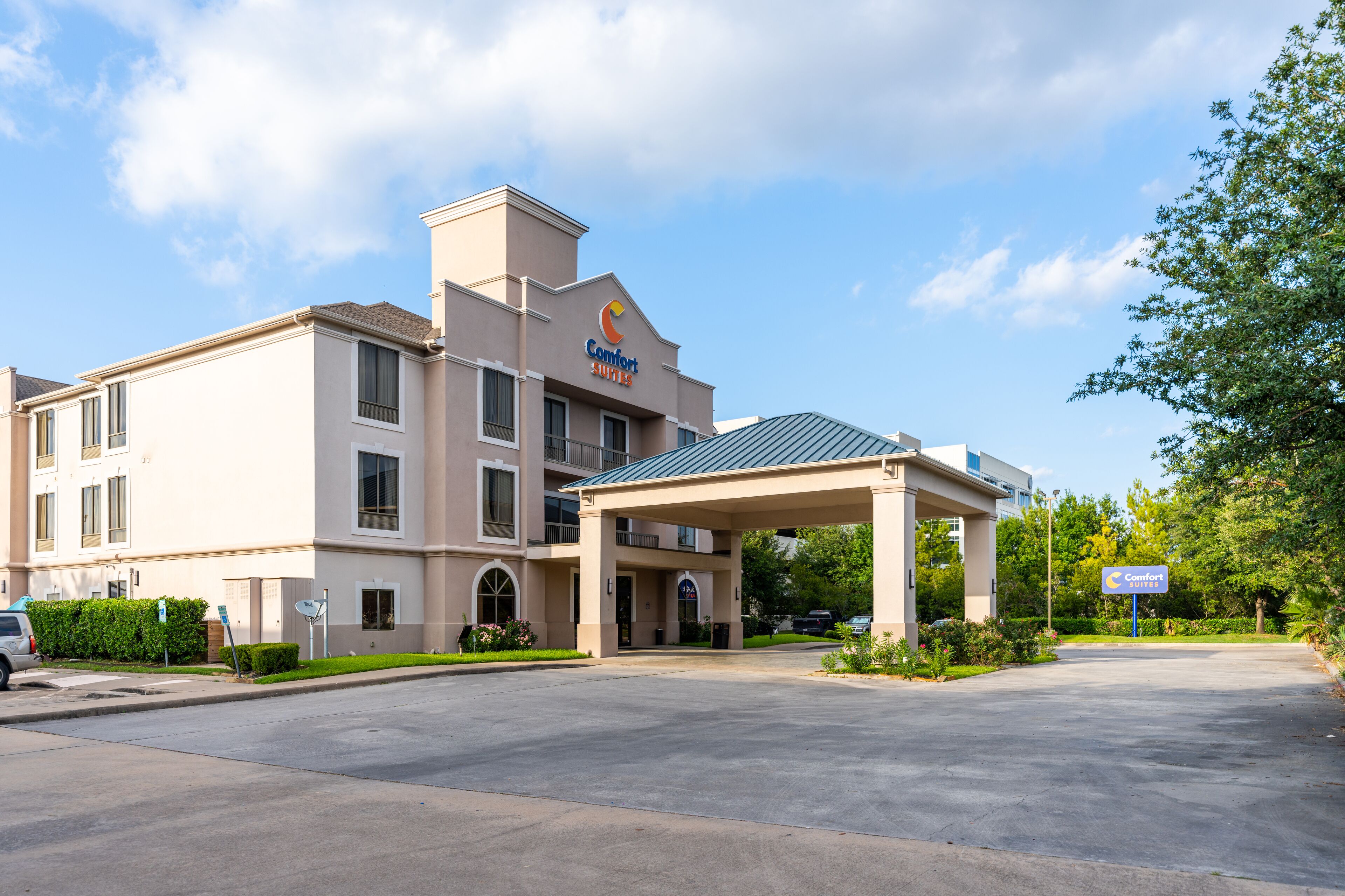 A Comfort Suites hotel with a covered entrance, multiple windows, and a parking lot.