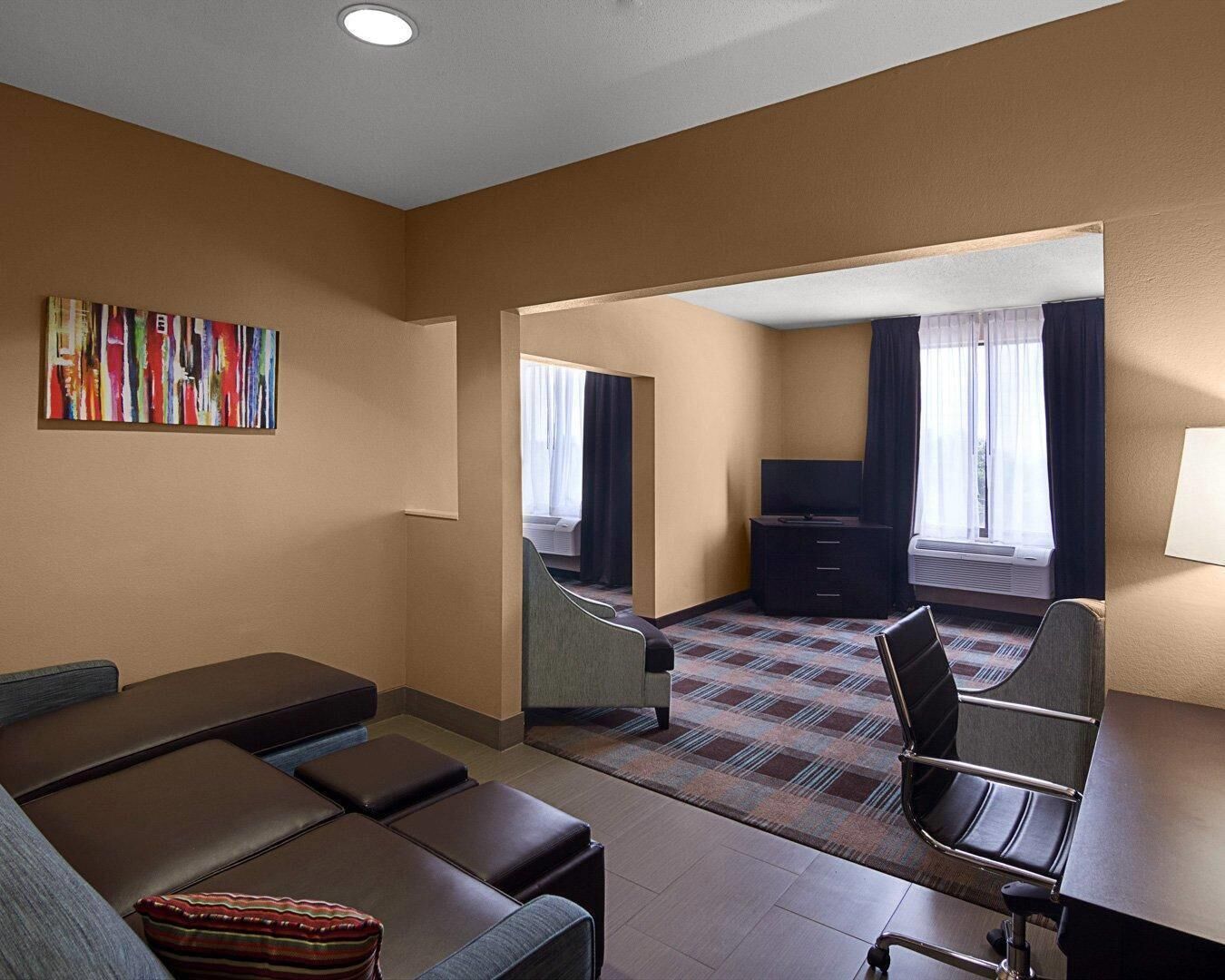 A hotel room with a sofa, a desk, a TV, and a bed.