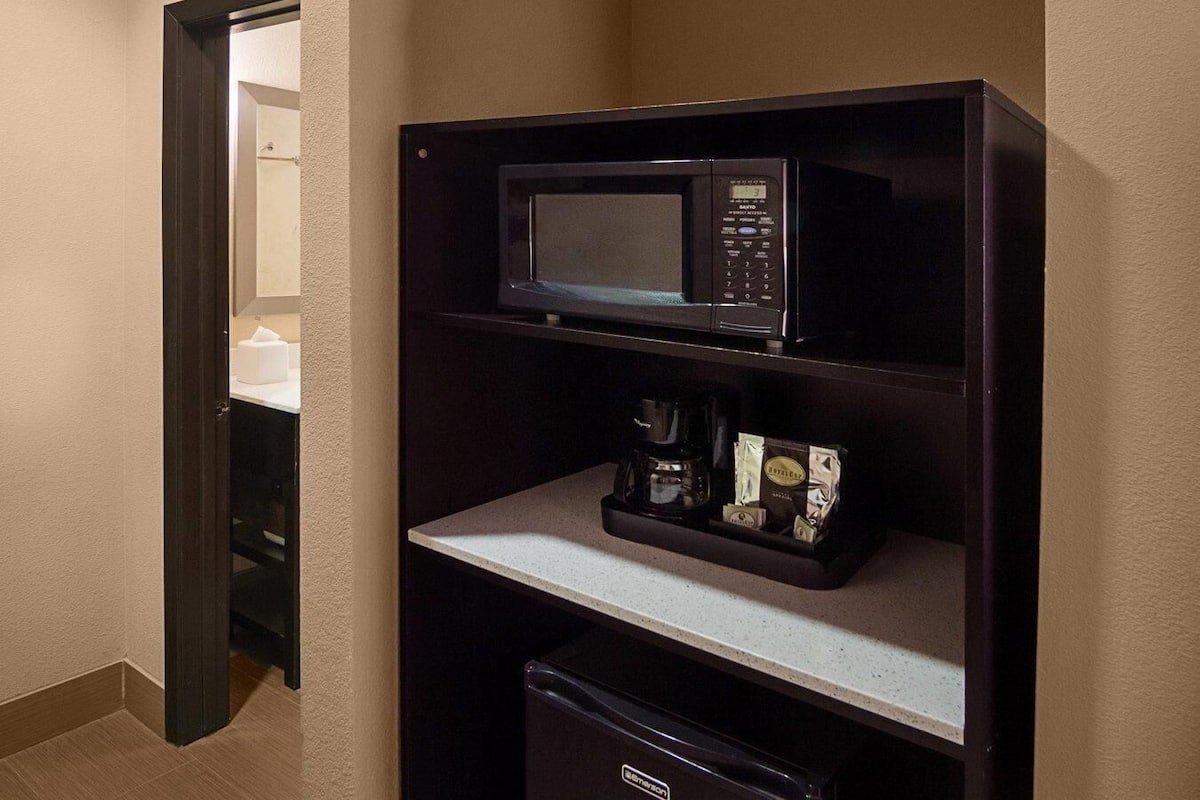 A compact kitchenette with a microwave, coffee maker, and a small refrigerator.