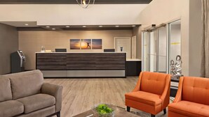 Un espace d’accueil moderne comprenant un bureau, deux canapés et une plante décorative.
