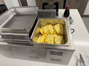 A buffet setup with a food container and a beverage dispenser.