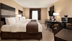 Une chambre d’hôtel avec un grand lit, un bureau avec un ordinateur, une télévision et un four à micro-ondes.
