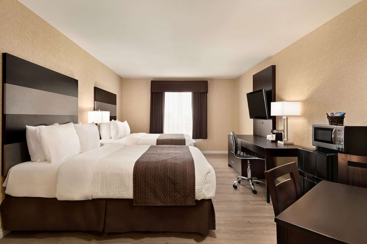 Habitación de hotel con una cama grande, un escritorio con computadora, televisión y microondas.
