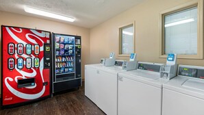 A laundry area with a vending machine and a washer-dryer unit. - Suburban Studios Louisville East  (Louisville)