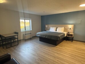 Una habitación de hotel con una cama, mesitas de noche, un escritorio y una silla.