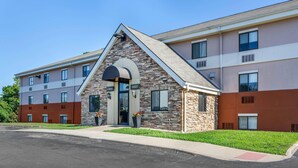 A multi-story hotel with a stone facade, a lobby entrance, and a parking lot. - Suburban Studios Louisville East  (Louisville)