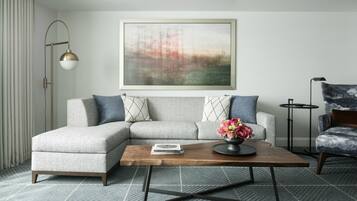 A modern living room with a sectional sofa, a coffee table, a floor lamp, and a painting on the wall.