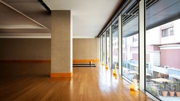 A spacious corridor with wooden flooring, large windows, and a view of outdoor seating.