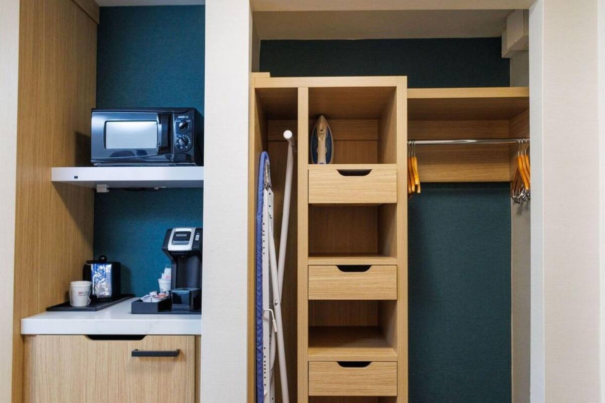 Cocina compacta con microondas, cafetera y cajones para guardar cosas.