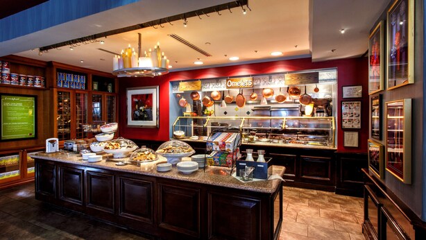 A buffet area with a variety of food items, a coffee station, and a sign reading "Omelets".