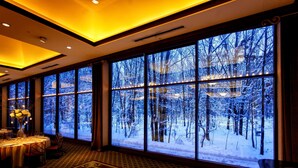 A room with large windows, a dining area, and a patterned carpet.