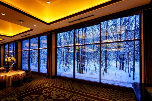 A room with large windows, a dining area, and a patterned carpet. - Hilton Garden Inn New York / Staten Island (Staten Island)