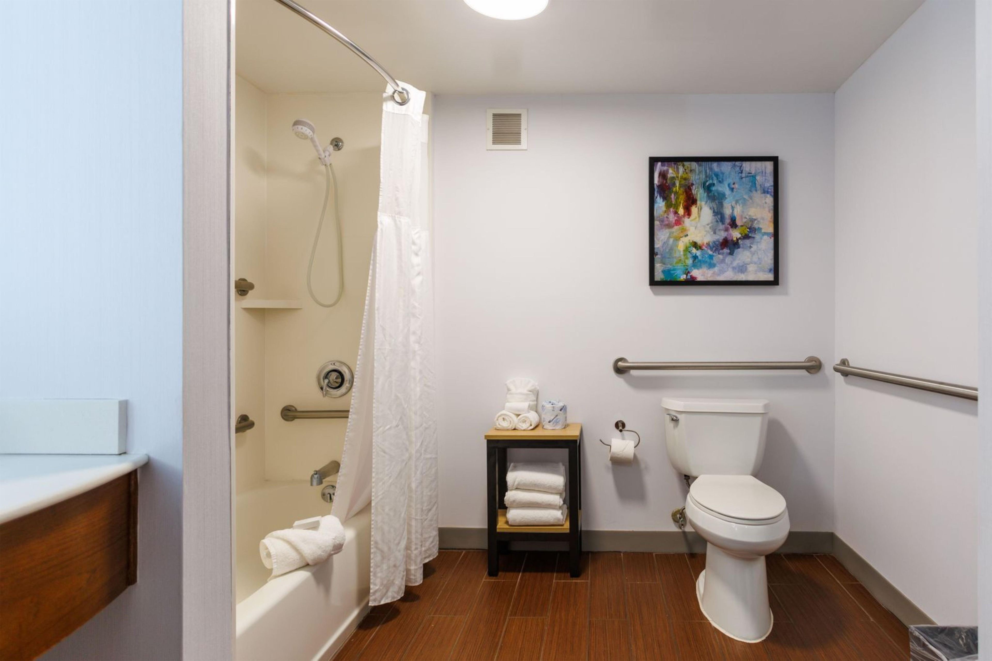 Une salle de bain avec douche, toilettes et une petite table avec des serviettes.