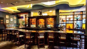 A bar area with a curved counter, multiple bar stools, and a variety of bottles and glasses.