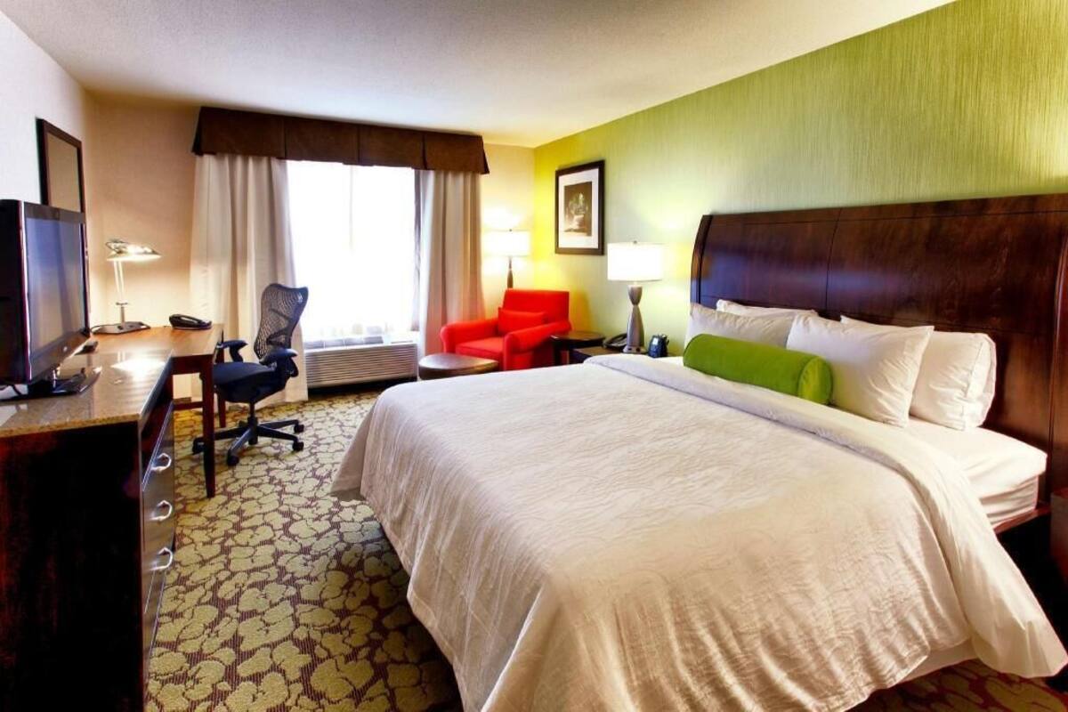 Habitación de hotel con cama, escritorio, silla y televisor.