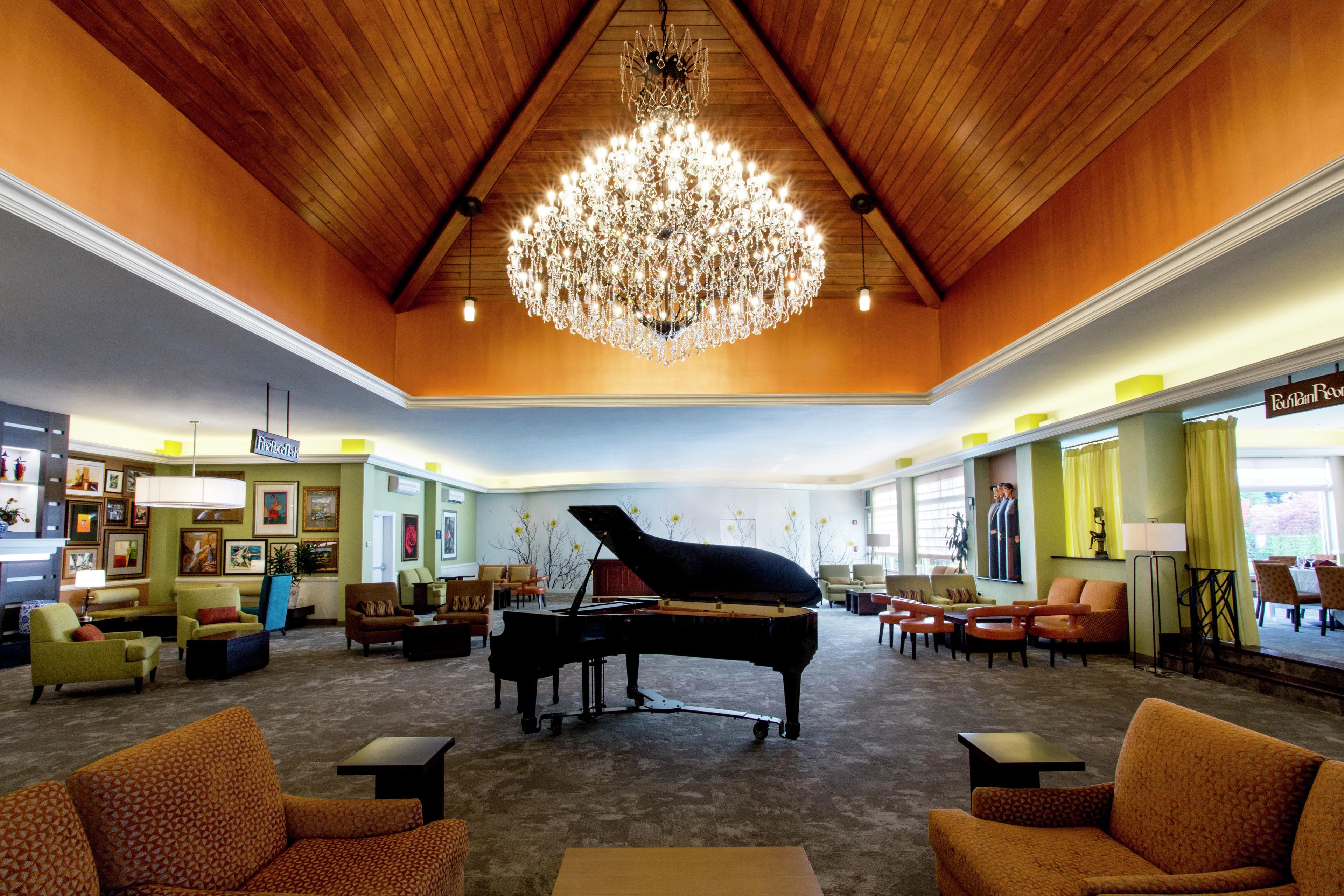 A grand lobby with a grand piano, comfortable seating, a chandelier, and a restaurant named 'Fountain Room'.