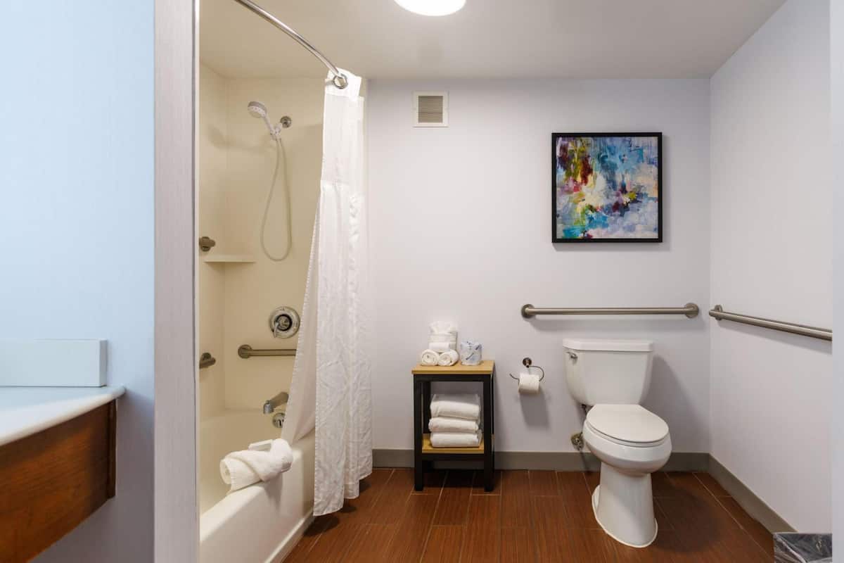 Un baño con ducha, inodoro y una pequeña mesa con toallas.