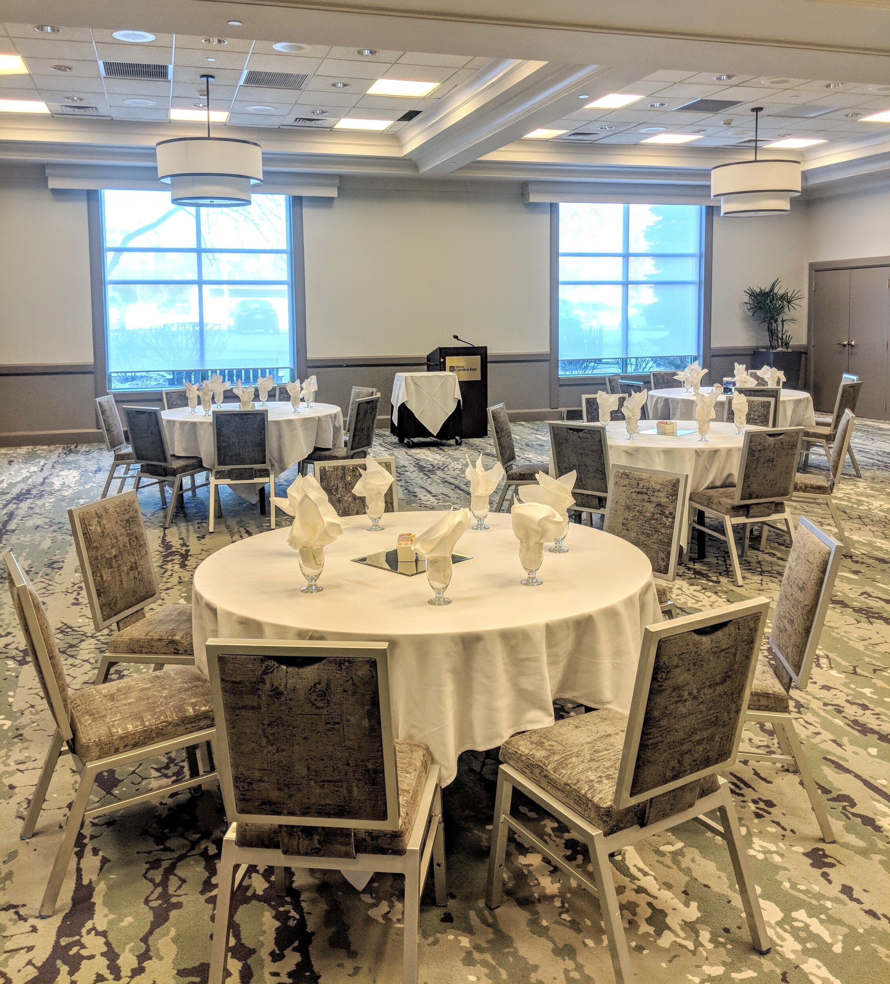 A conference room with round tables, chairs, and a podium.