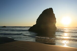 A rock formation by the sea during sunset.