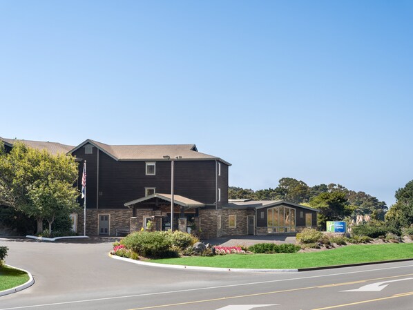 Hotel entrance with covered walkway and beautifully landscaped grounds.