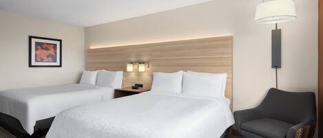 A hotel room with two beds, a desk, a chair, a lamp, and a framed picture on the wall.