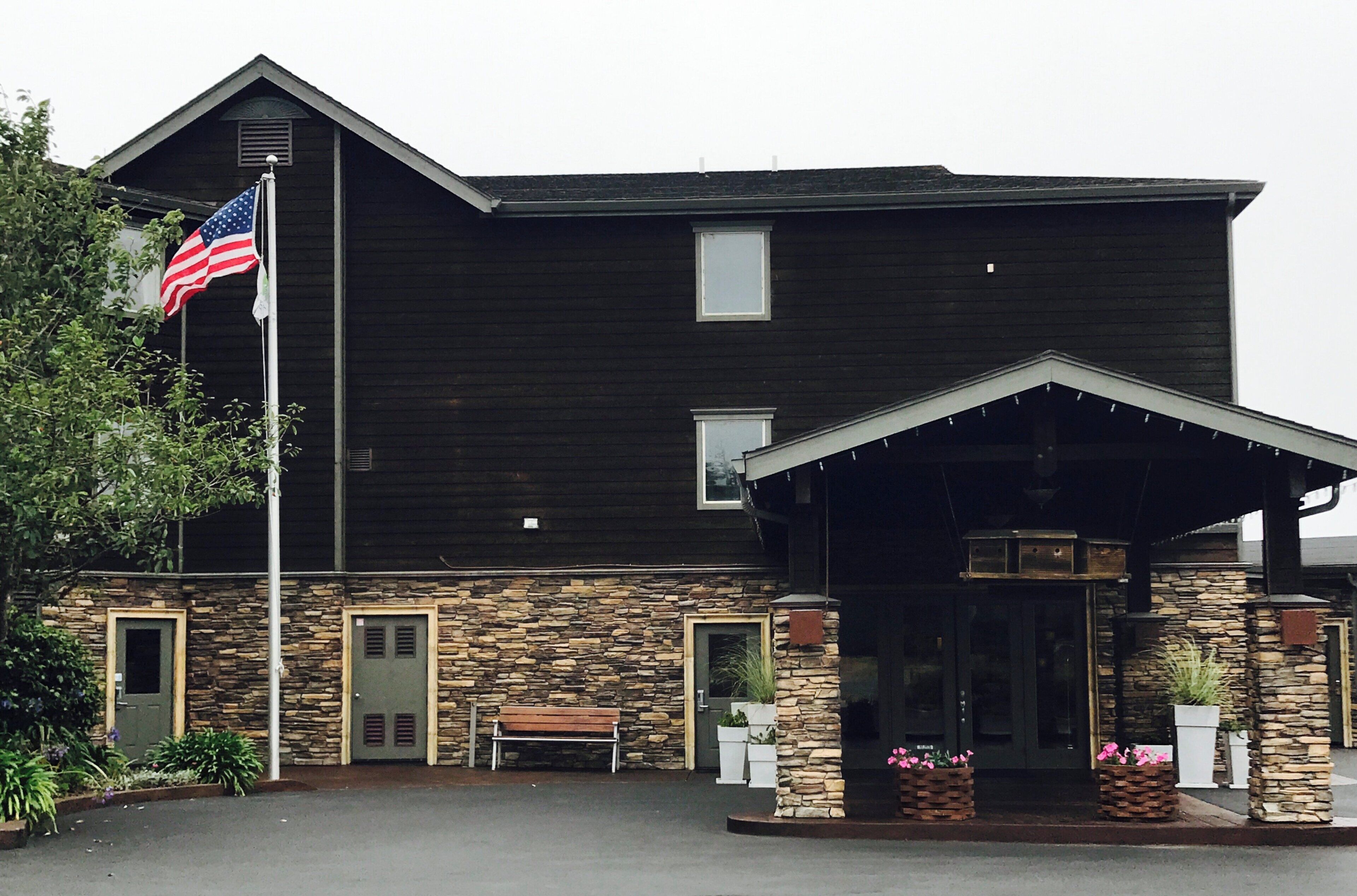 A building with a stone facade, a flag, and a covered entrance.