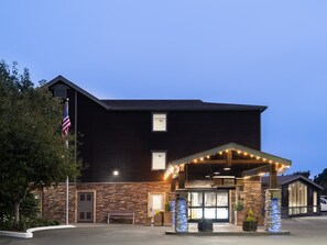 Welcome to our hotel, featuring a covered entrance with a bench and lush greenery.