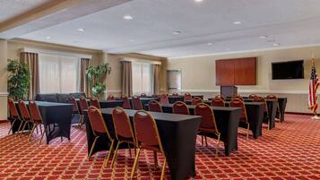 A conference room with tables and chairs, a television, and an American flag.