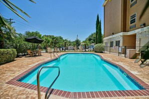 Una piscina al aire libre, sombrillas, sillones reclinables de piscina