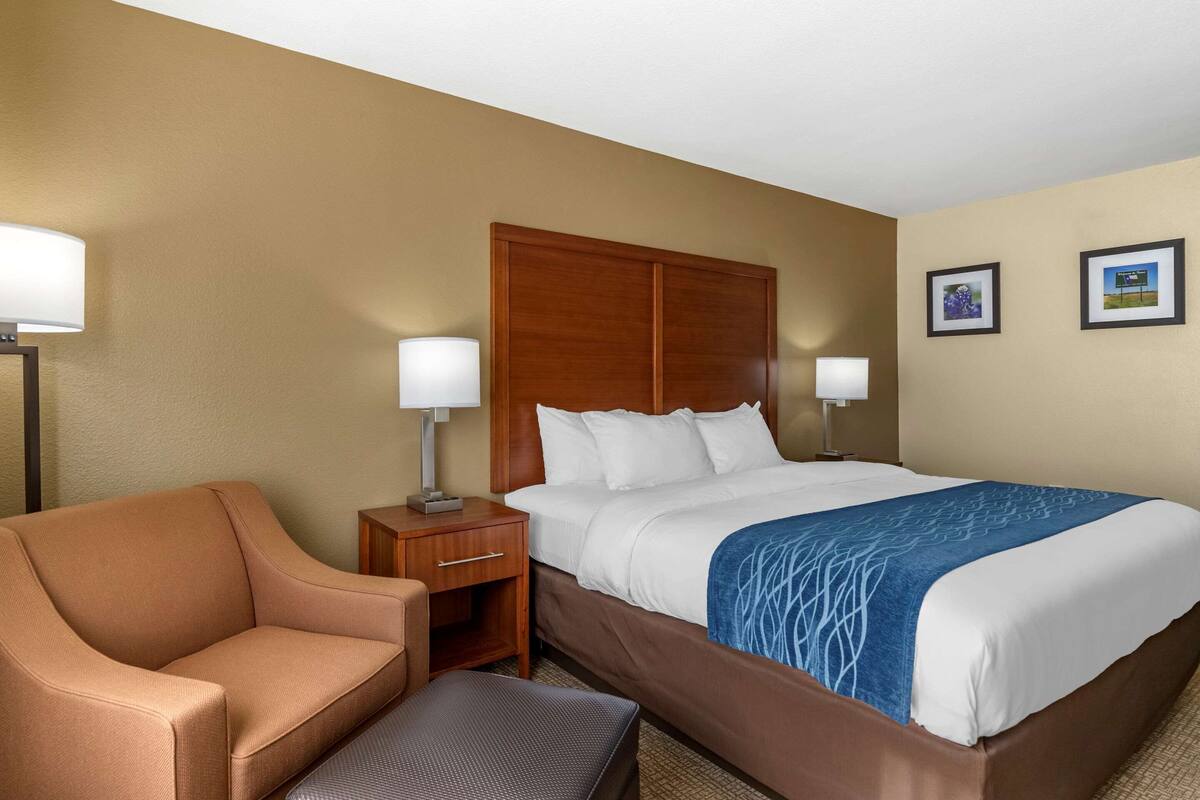 Una habitación de hotel con cama, mesita de noche, una silla y un escritorio.