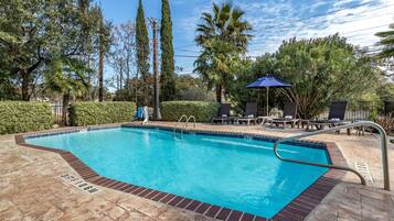 Una piscina al aire libre, sombrillas, sillones reclinables de piscina