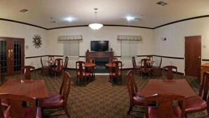 A conference room with a fireplace, a television, and multiple tables and chairs. - Holiday Inn Express Hotel & Suites Dayton West - Brookville by IHG (Brookville)
