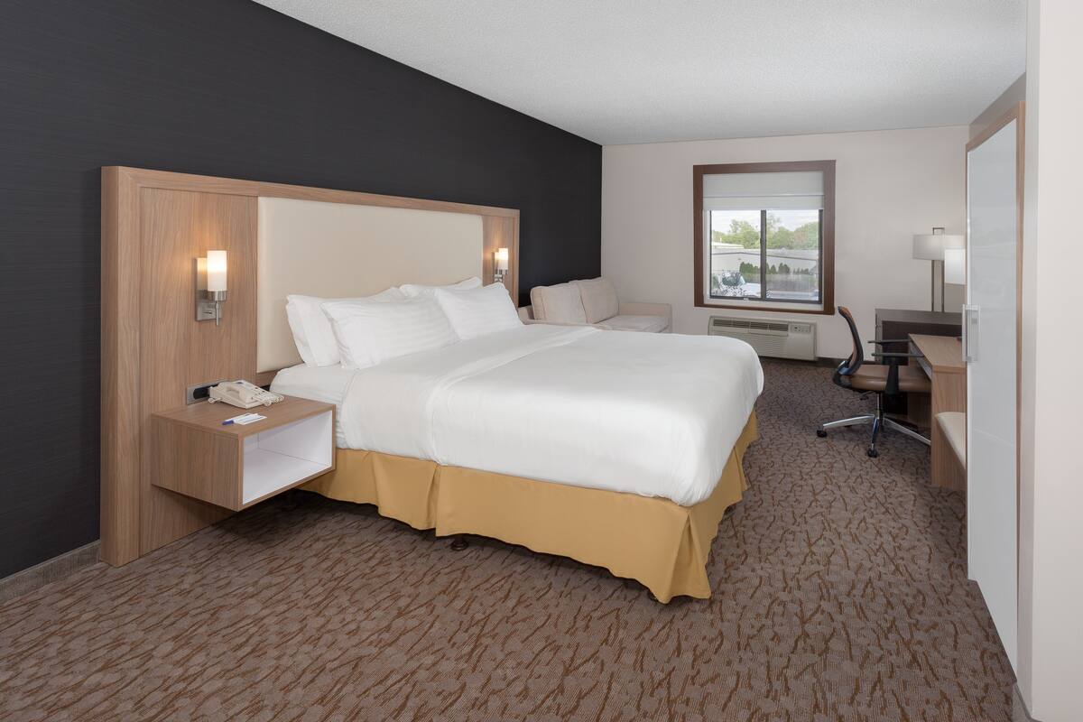 A hotel room with a large bed, bedside tables, a desk, and a chair.