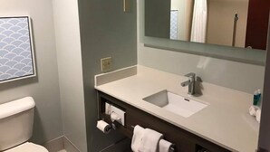 Un baño con inodoro blanco, lavamanos con espejo y una toalla colgada en la pared.